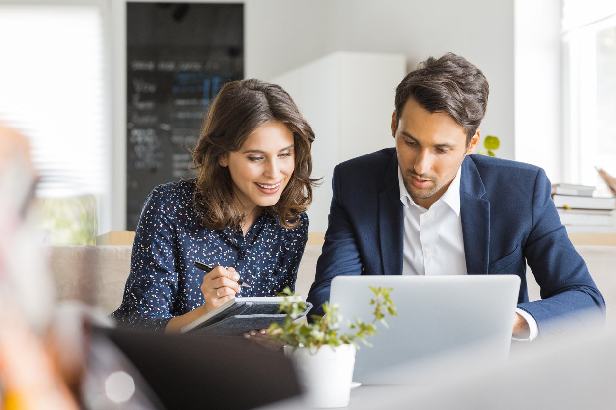 man-and-woman-sitting-at-table-while-working-on-laptop-together