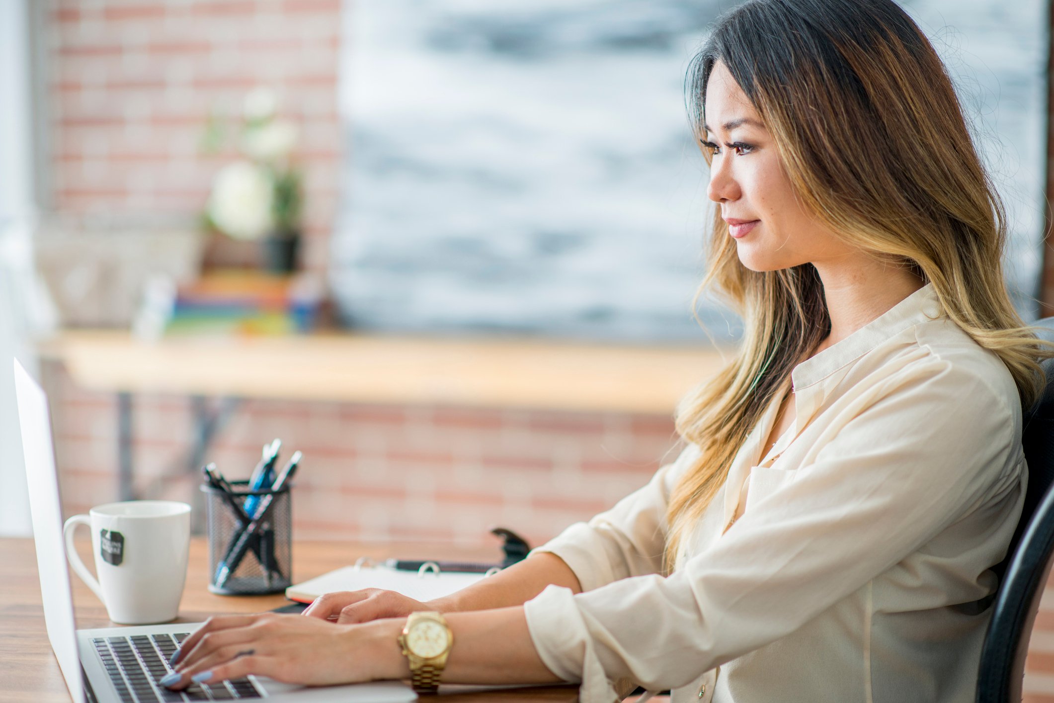 woman-wearing-professional-attire-sitting-at-desk-working-on-laptop-on-email-marketing-campaign