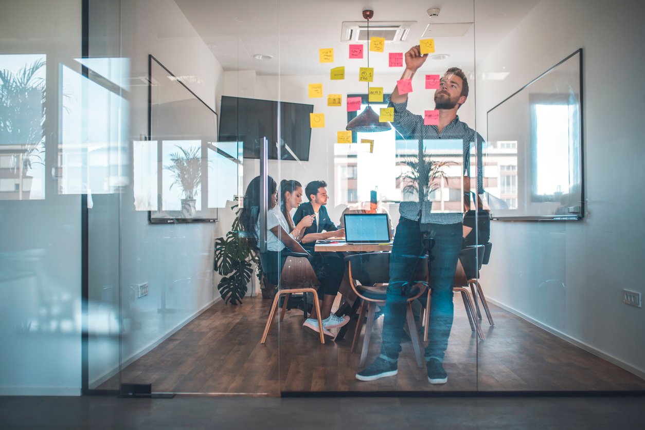 Marketing team brainstorming putting sticky notes on glass wall